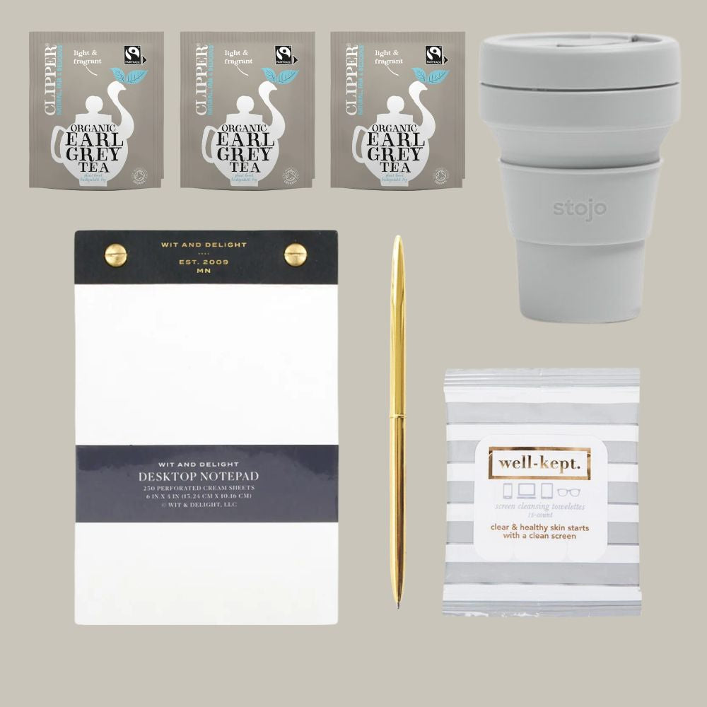 Collection of items including Clipper tea packages, a Stajo cup, a desktop notepad, a pen, and a well-kept product on a neutral background.