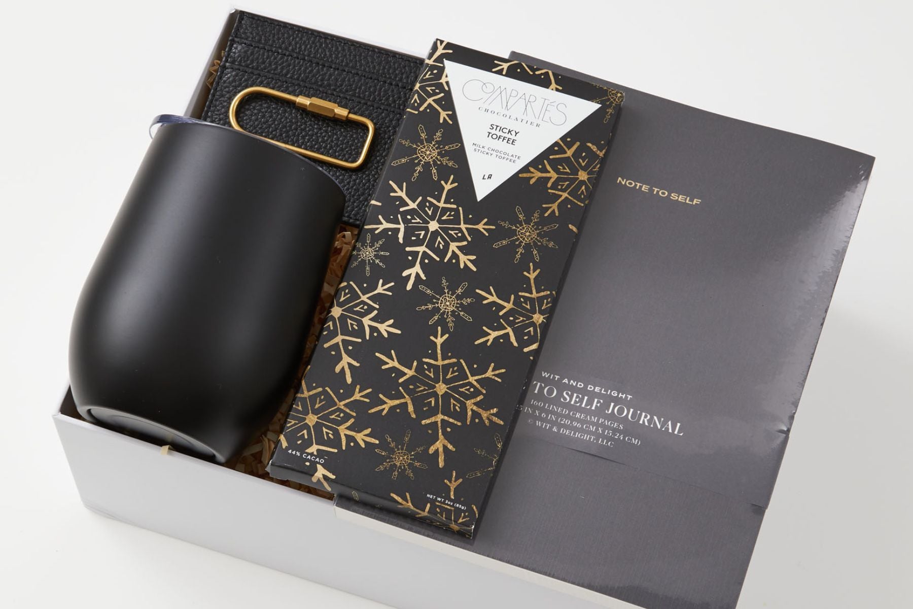 Black mug and journal in a gift box with chocolate bar.